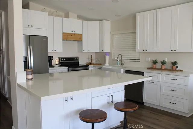 a kitchen with stainless steel appliances granite countertop a sink a stove and white cabinets