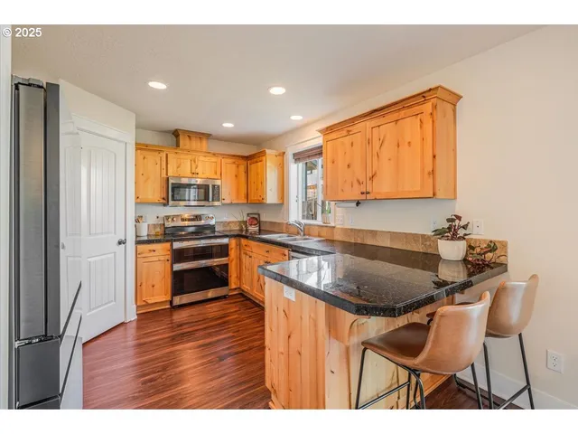 a kitchen with stainless steel appliances granite countertop a sink a stove and a refrigerator