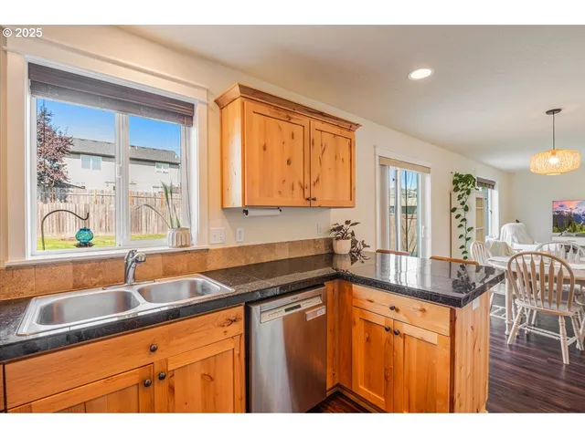 a kitchen with stainless steel appliances granite countertop a refrigerator a sink and white cabinets with wooden floor