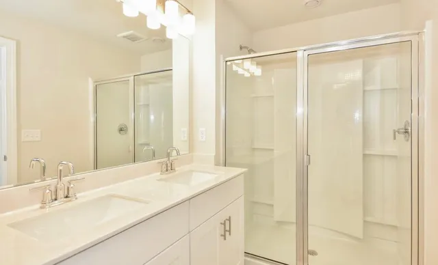 a bathroom with a granite countertop sink mirror and a shower