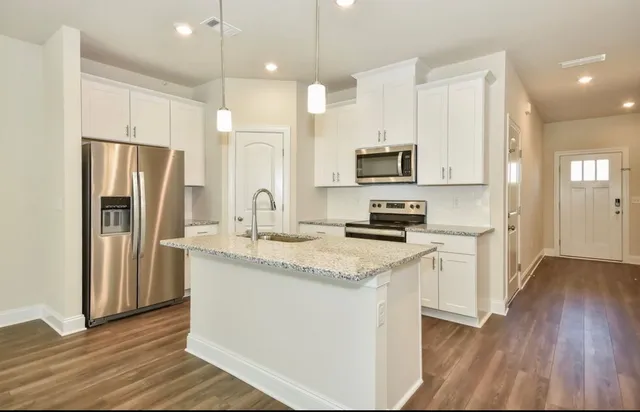 a kitchen with stainless steel appliances granite countertop a refrigerator a stove a sink and a microwave