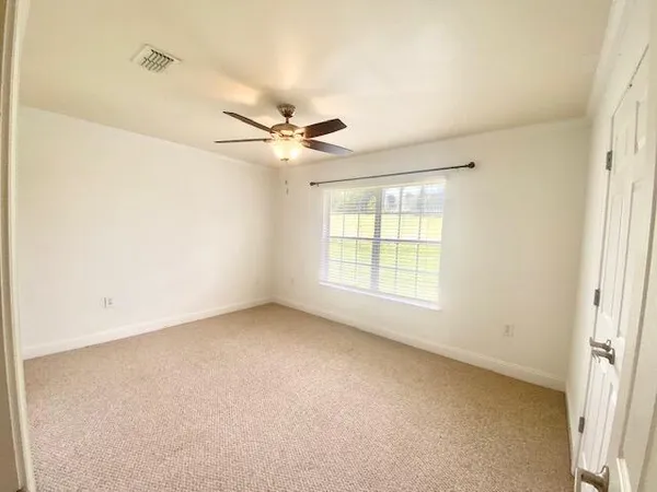 an empty room with windows and fan