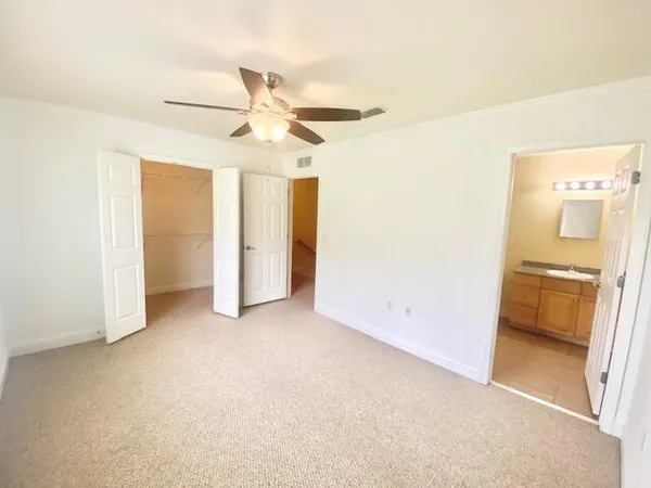 an empty room with closet and a ceiling fan