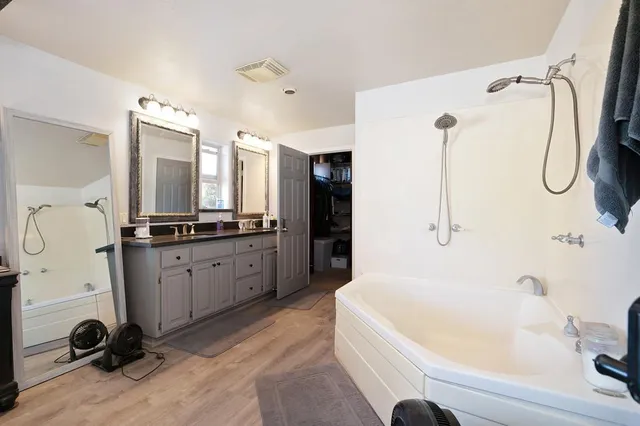 a bathroom with a tub sink and mirror