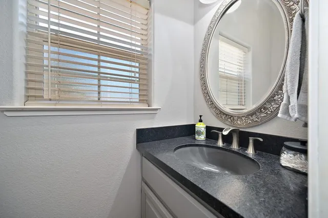 a bathroom with a granite countertop sink and a mirror