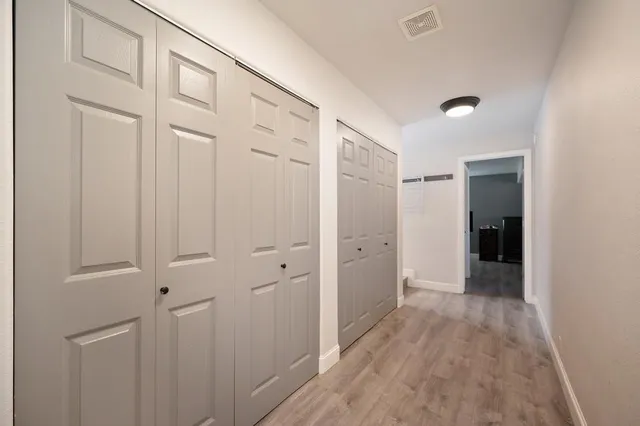 a view of a hallway with wooden floor and closet area