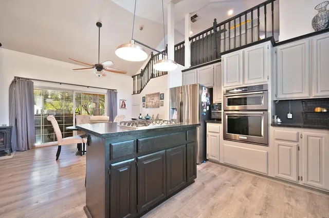 a kitchen with stainless steel appliances granite countertop a refrigerator a stove and a wooden floors