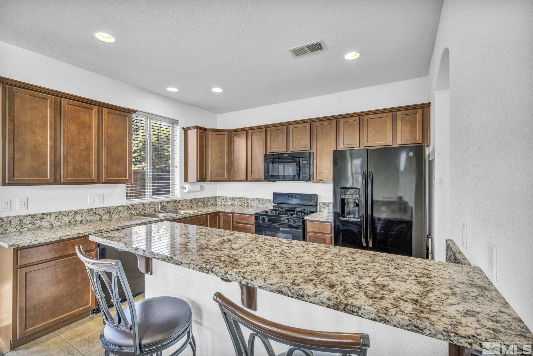 2705 Gulling Court Reno, NV 89503 - Photo 5 of 40 a kitchen with granite countertop a refrigerator and wooden cabinets