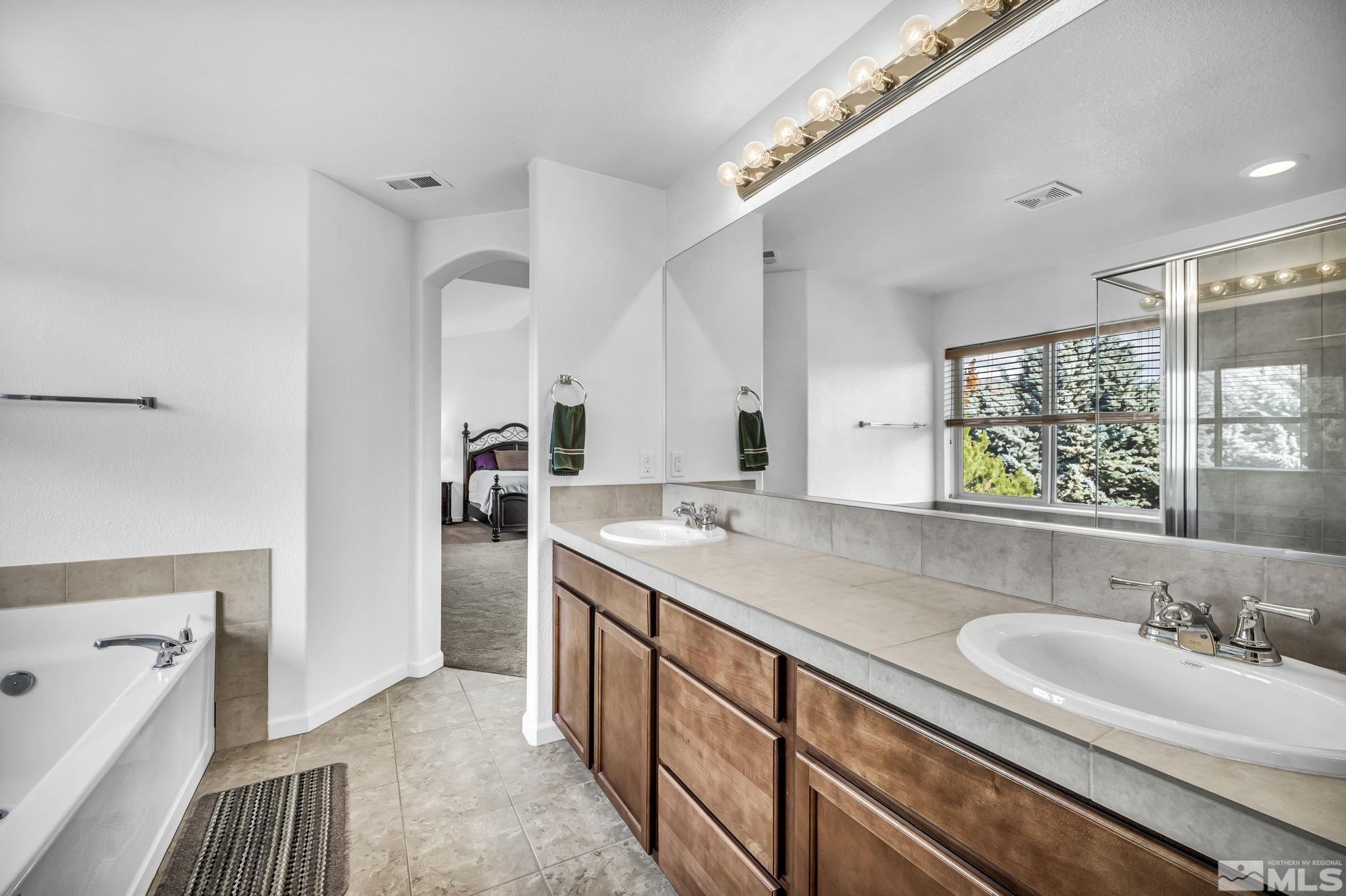 2705 Gulling Court Reno, NV 89503 - Photo 10 of 40 a bathroom with a granite countertop sink a large mirror and a bathtub
