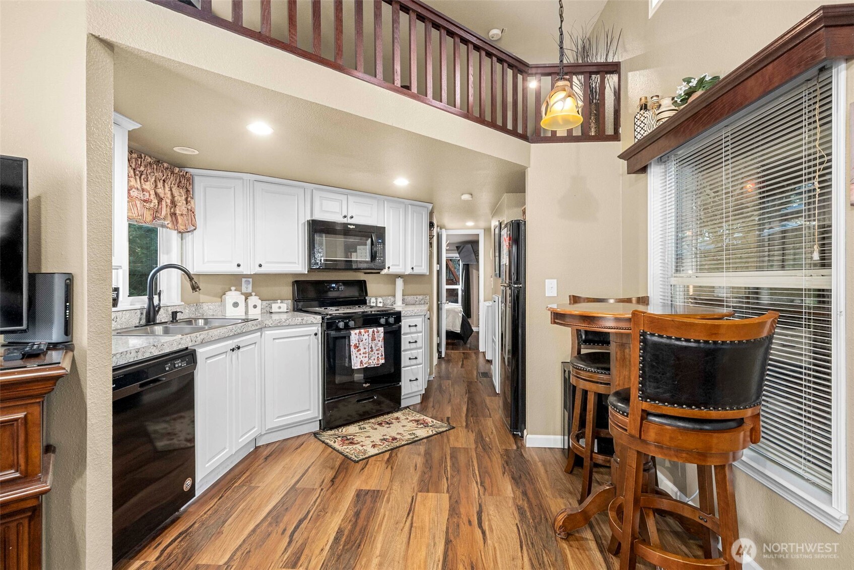 1546 Reservation Road Southeast, Unit 218 Olympia, WA 98513 - Photo 5 of 40 a kitchen with stainless steel appliances kitchen island granite countertop a refrigerator a stove a sink a dining table and chairs with wooden floor