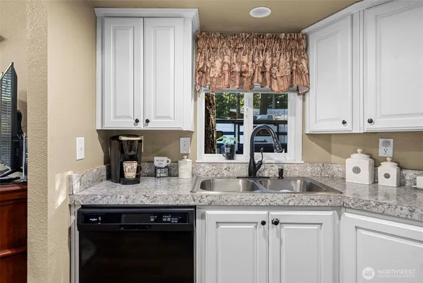 a kitchen with granite countertop a sink a stove and cabinets