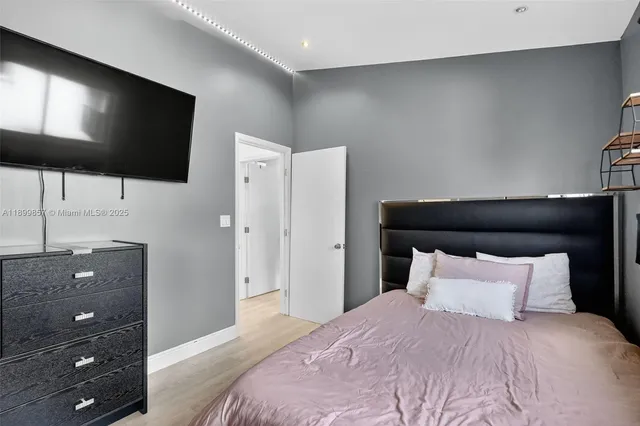 a bedroom with a bed and a flat tv screen on dresser