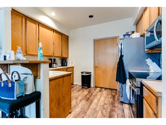 a open kitchen with stainless steel appliances granite countertop a refrigerator a sink dishwasher and wooden cabinets with wooden floor