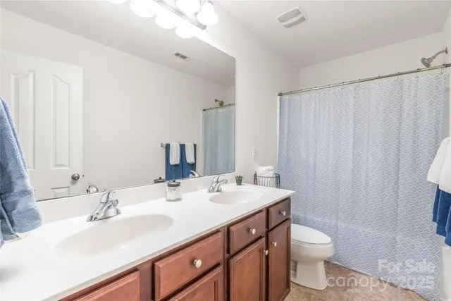 a bathroom with a double vanity sink toilet and a mirror