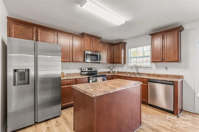 a kitchen with stainless steel appliances granite countertop a refrigerator a sink a stove a microwave and island