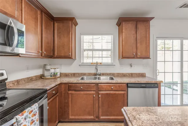 a kitchen with granite countertop cabinets stainless steel appliances a sink and window