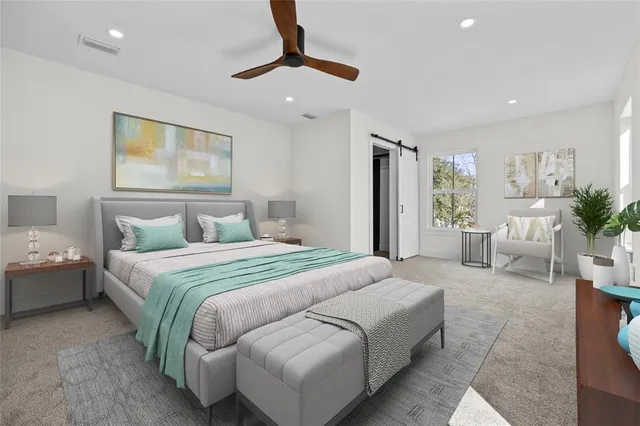 a bedroom with a large bed couch and windows