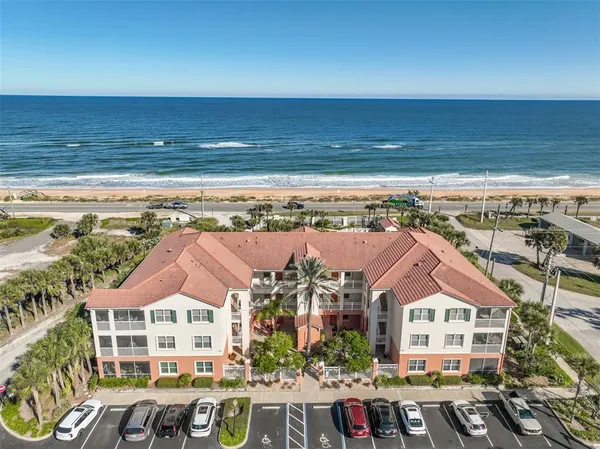 an aerial view of ocean and residential houses with outdoor space