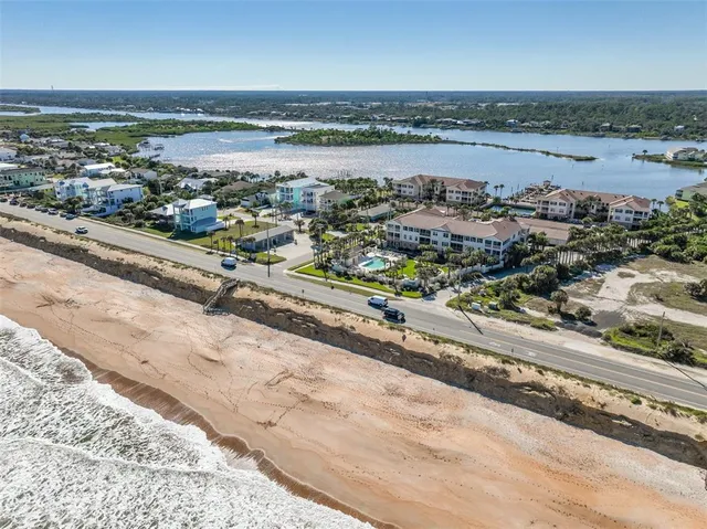 an aerial view of ocean and residential houses with outdoor space