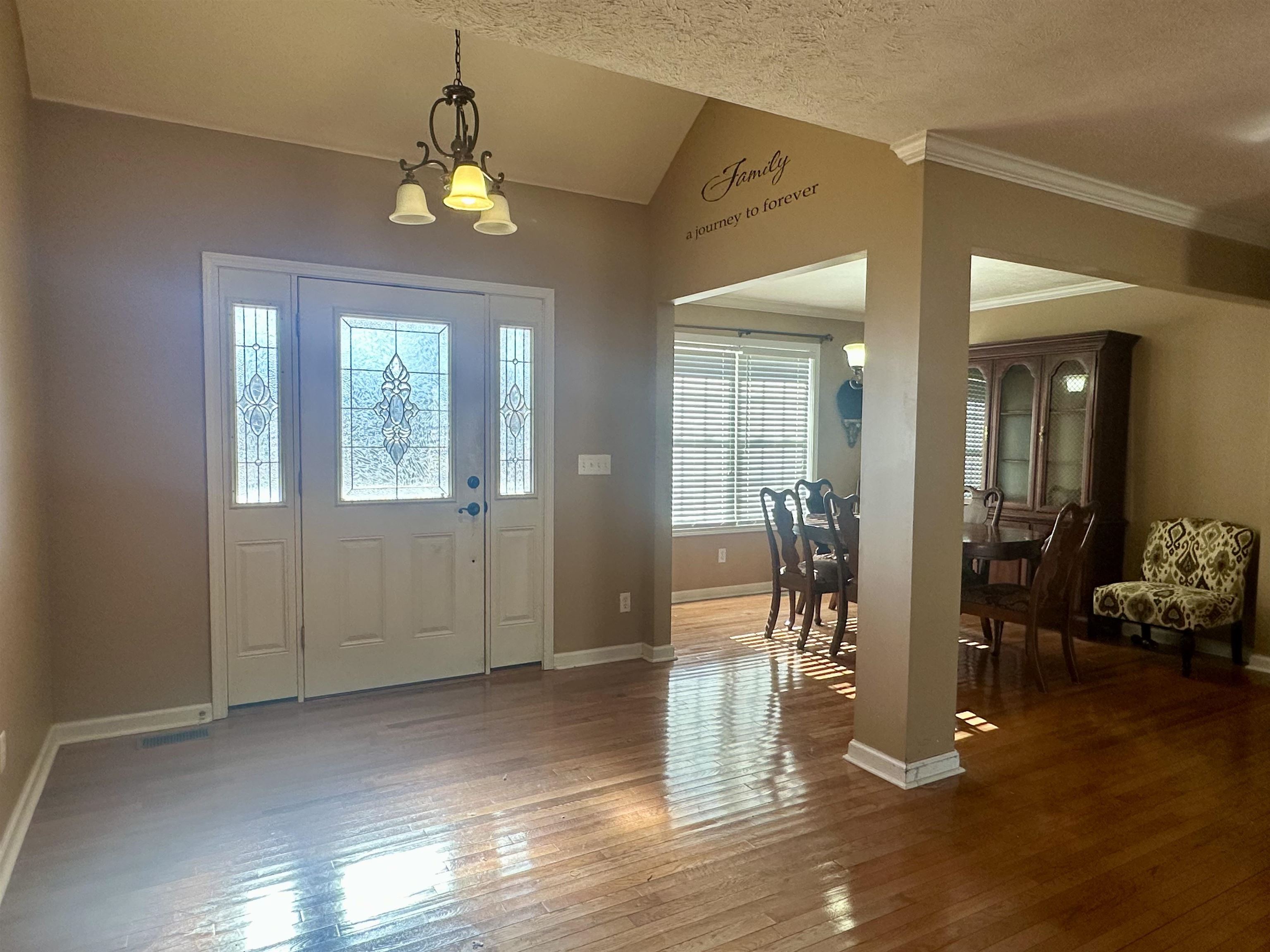 133 Arrowhead Trail Adamsville, TN 38310 - Photo 6 of 24 Entrance foyer with a textured ceiling, lofted ceiling, an inviting chandelier, hardwood / wood-style flooring, and crown molding