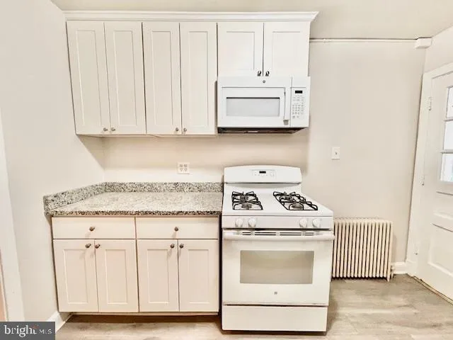 a kitchen with white cabinets and white appliances