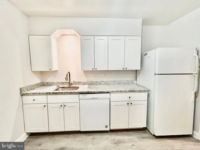a kitchen with granite countertop white cabinets and a refrigerator