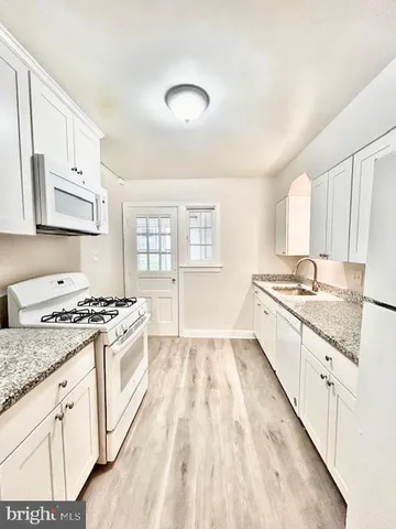 a kitchen with granite countertop a sink stove and cabinets