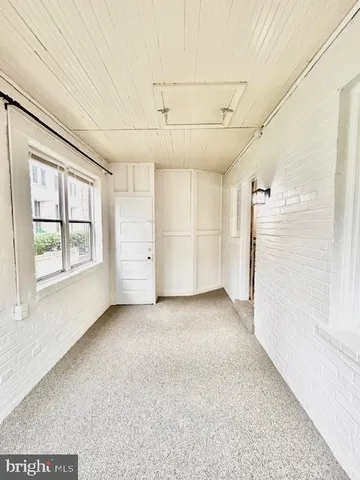 a view of a livingroom with an empty space & a window