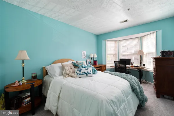 a bedroom with bed a lamp and a window