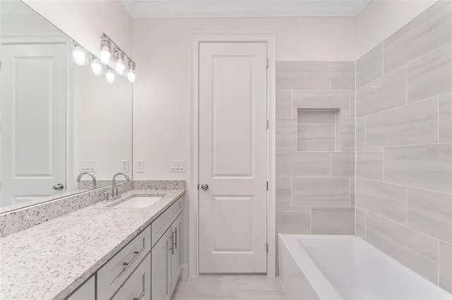 a bathroom with a granite countertop sink a mirror and a bathtub