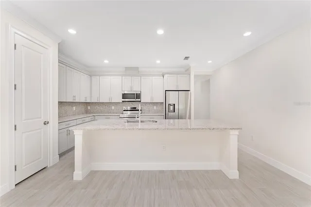 a large white kitchen with wooden floor and a window