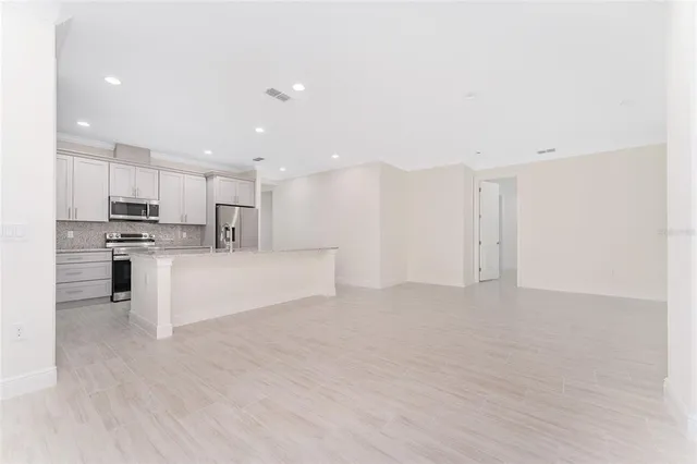 a view of kitchen with kitchen island stainless steel appliances sink and cabinets