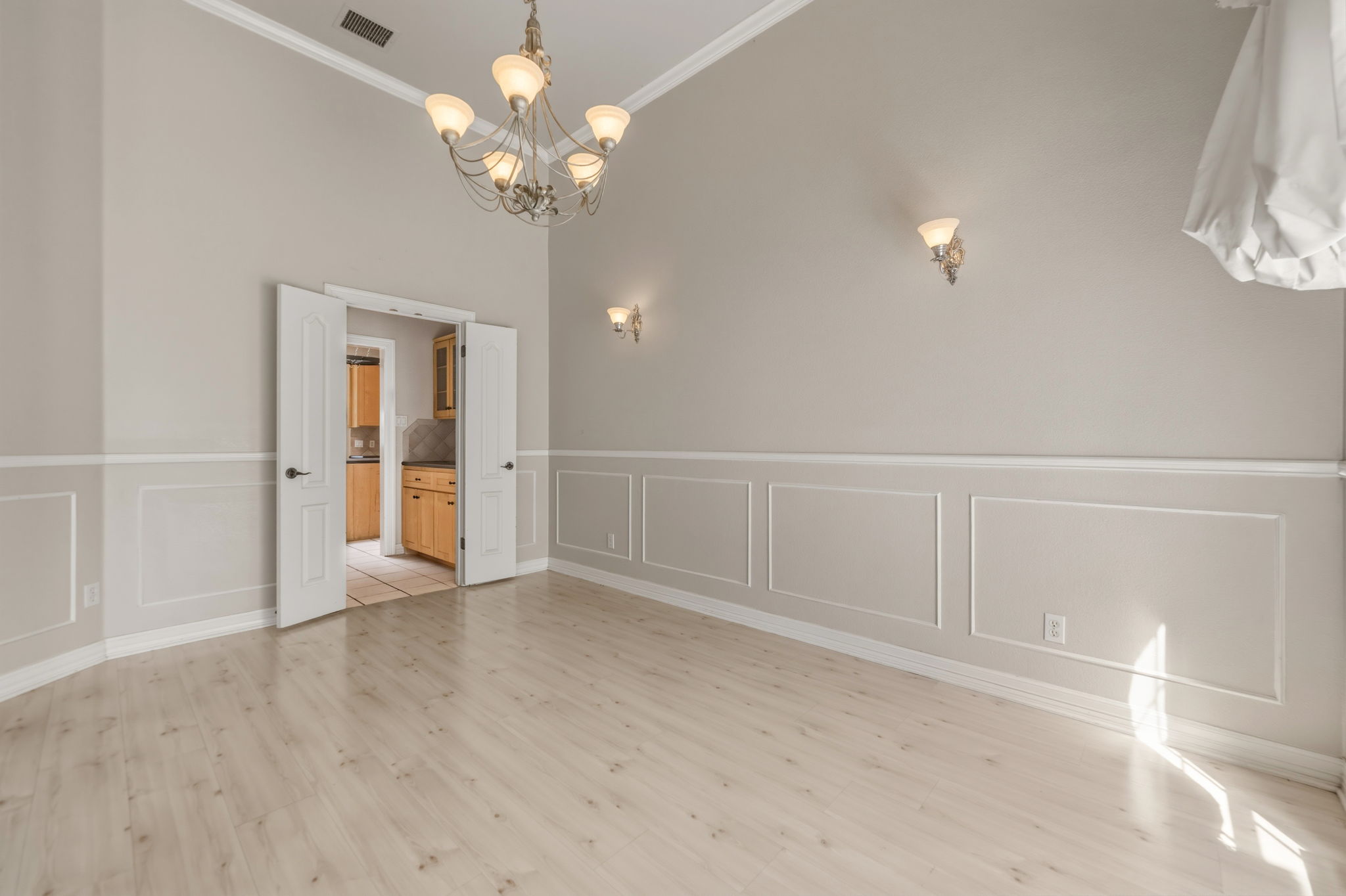 14039 Timberline Trail Austin, TX 78737 - Photo 11 of 39 Unfurnished dining area with a chandelier, ornamental molding, a decorative wall, wainscoting, and light wood-style floors