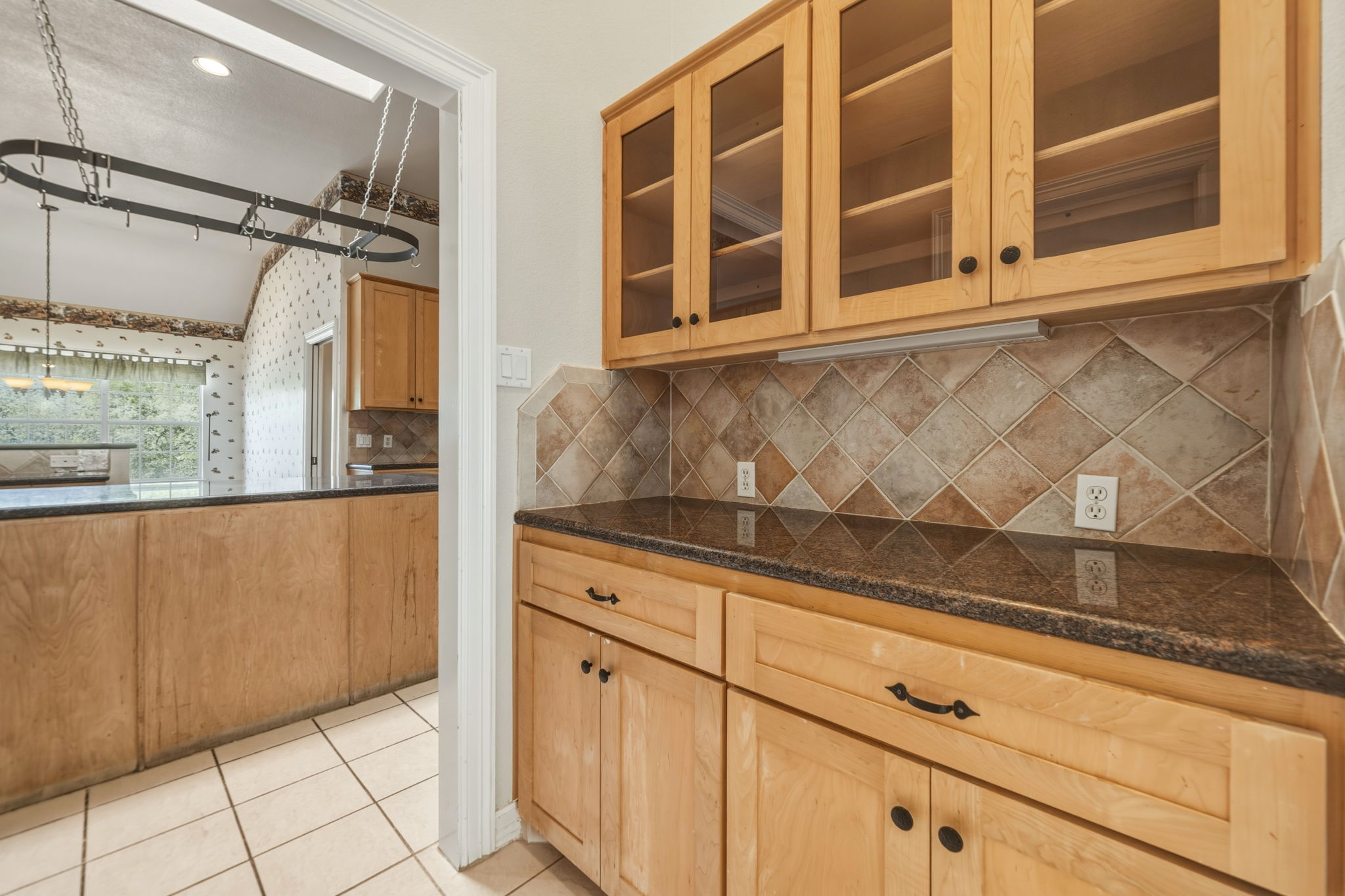 14039 Timberline Trail Austin, TX 78737 - Photo 13 of 39 Kitchen featuring glass insert cabinets, dark stone countertops, tasteful backsplash, light tile patterned floors, and pendant lighting