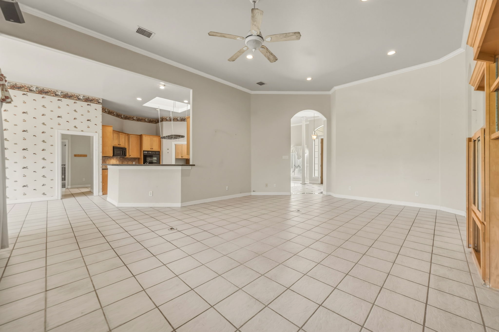 14039 Timberline Trail Austin, TX 78737 - Photo 18 of 39 Unfurnished living room with crown molding, a ceiling fan, arched walkways, recessed lighting, and light tile patterned floors