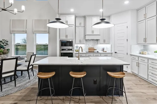 a kitchen with stainless steel appliances a dining table chairs and white cabinets