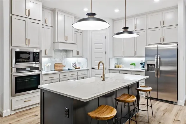 a kitchen with a sink a kitchen island and stainless steel appliances