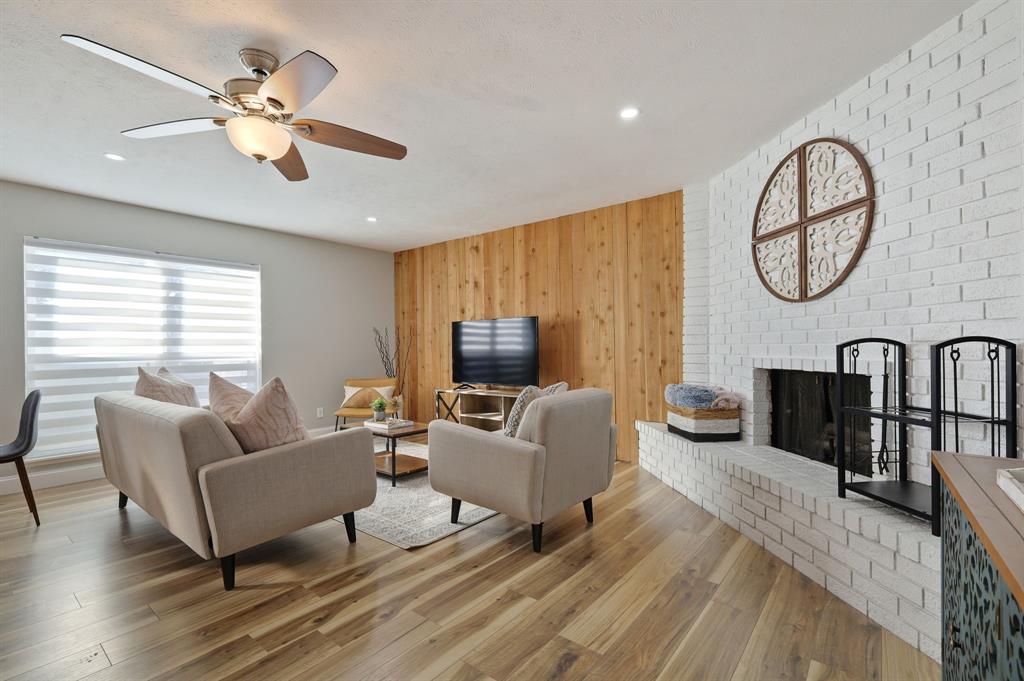5112 Arbor Glen Road The Colony, TX 75056 - Photo 16 of 40 Living room featuring ceiling fan, a fireplace, wood-type flooring, and wooden walls