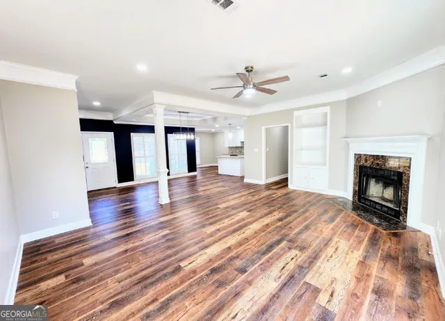 a view of an empty room with wooden floor fireplace and a window
