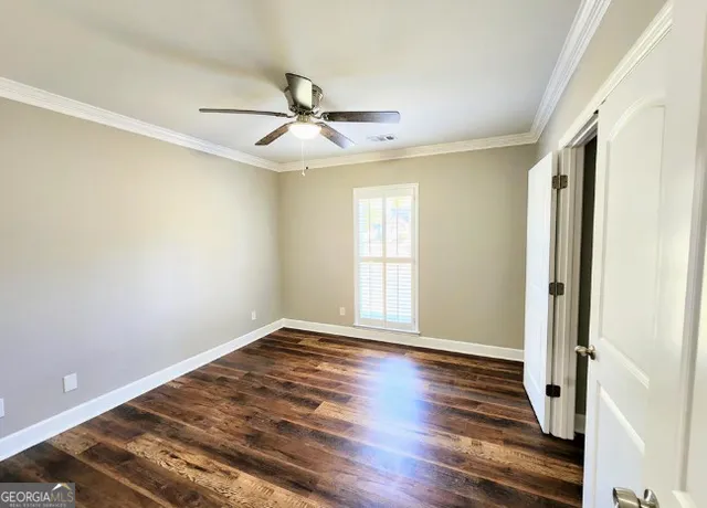 an empty room with wooden floor fan and windows