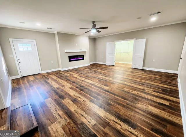a view of empty room with wooden floor and fan