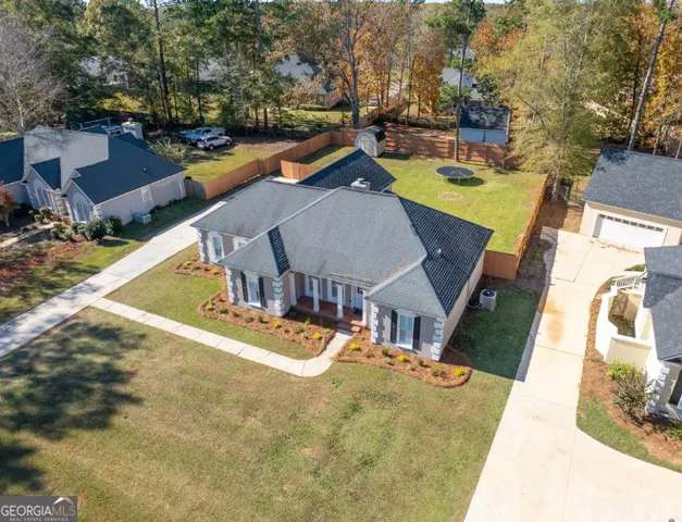 an aerial view of a house with swimming pool and large trees