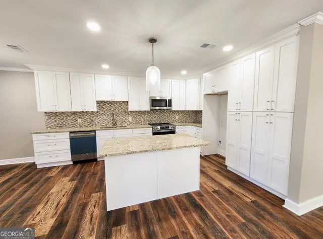 a kitchen with stainless steel appliances granite countertop a stove a sink and a refrigerator