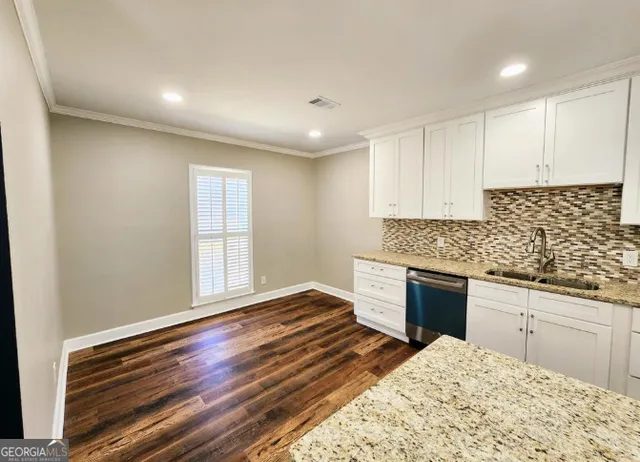 a kitchen with granite countertop a stove cabinets and wooden floor