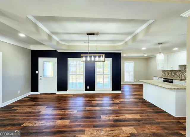 a view of an empty room with kitchen and window