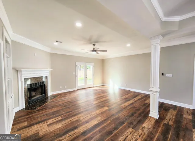 an empty room with wooden floor fireplace and windows