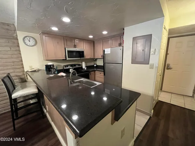 a living room with stainless steel appliances furniture a rug and a view of kitchen
