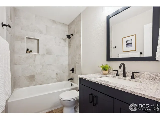 a bathroom with a granite countertop bathtub sink vanity mirror and toilet