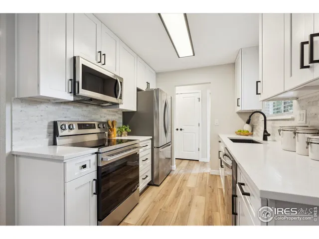 a kitchen with stainless steel appliances white cabinets a sink a stove a refrigerator and a microwave
