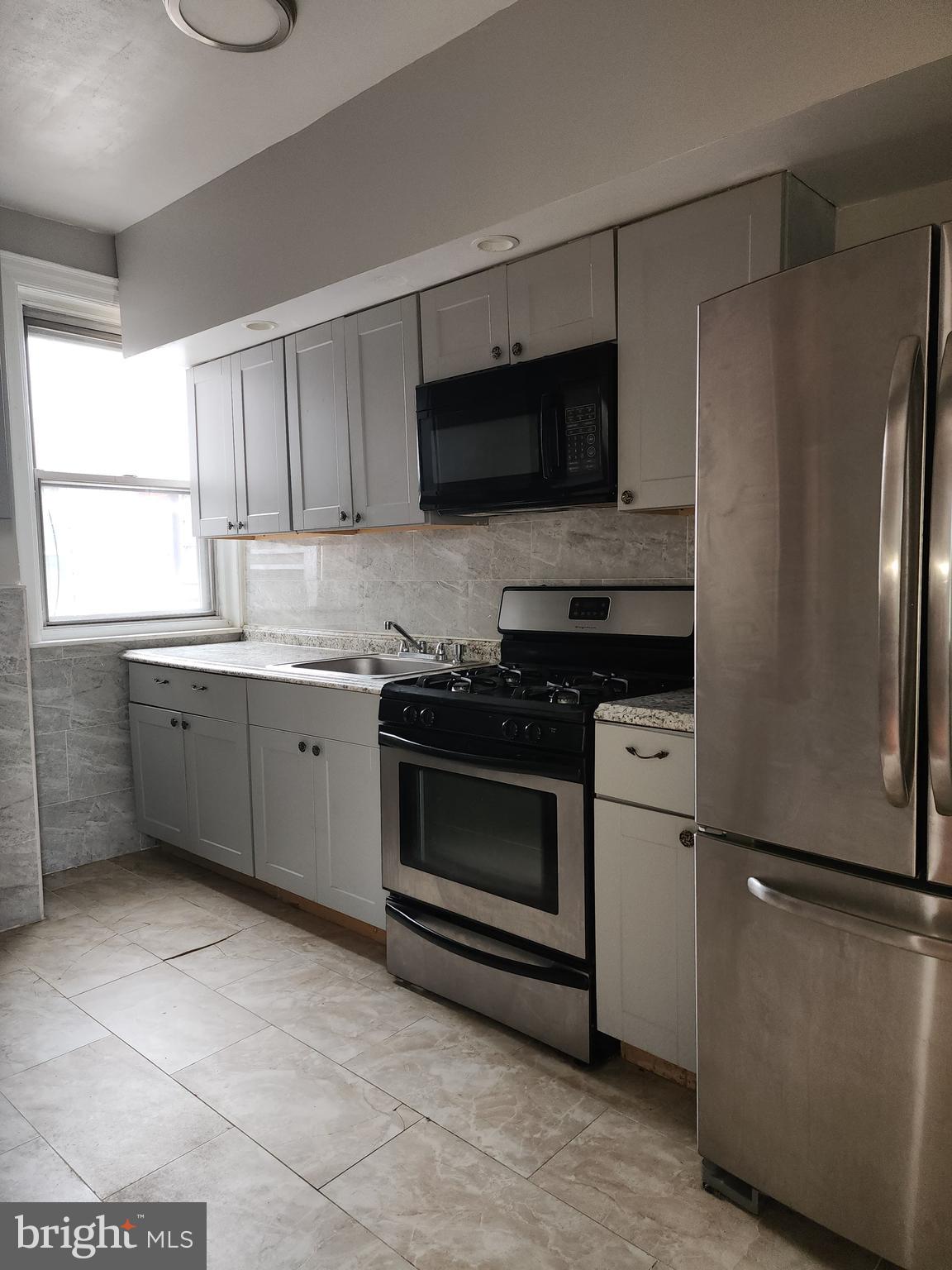 217 South 47th Street, Unit 2 Philadelphia, PA 19139 - Photo 17 of 22 a kitchen with stainless steel appliances a refrigerator sink and microwave